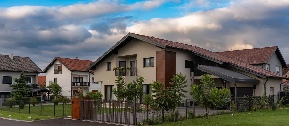 Einfamilienhäuser mit Satteldach, Zaun, Rasen und eigener Zufahrt an einer ruhigen Siedlungsstraße